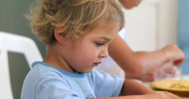 Küçük çocuk sabah kahvaltıda yuvarlanıp krep yiyor.