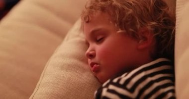 Baby boy asleep in living-room sofa in front of TV screen