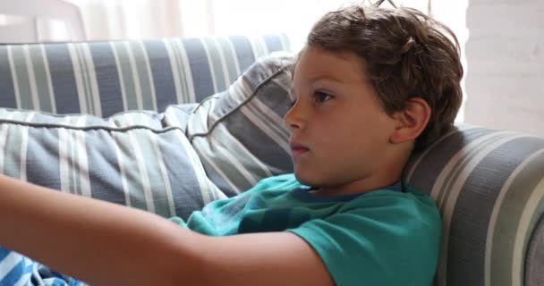 若いです男の子でホームソファ見ますテレビ — ストック動画