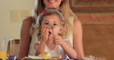 Anne kucağında yemek yiyen çocuk.