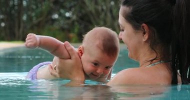 Mother and baby at the swimming pool holding toddler son