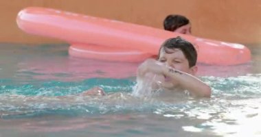 Çocuklar yüzme havuzunda su sıçratmaca oynuyorlar.