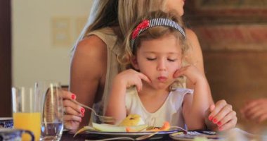 Anne kucağında yemek yiyen çocuk.