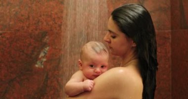 Mother holding newborn baby in the shower, bathing and washing infant