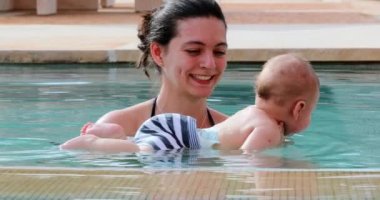 Newborn baby inside swimming pool water with mother