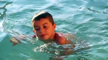 Çocuk havuzda ağır çekimde yüzüyor. Havuz kenarında 120fps tutuyor.