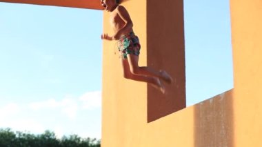 Küçük çocuk yavaş çekimde havuza atlıyor. 