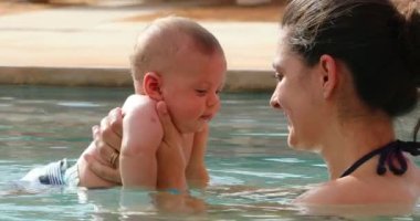 Mother and newborn baby at swimming pool water interaction