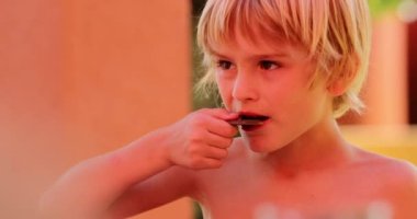 Dışarıda kurabiye yiyen genç bir çocuk. Şekerli çocuk tatlı yiyor.