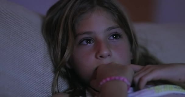 女の子顔見ますテレビスクリーンオンリビングルームのソファ夜に暗闇の中で — ストック動画