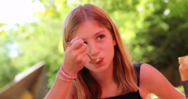 Çocuk, öğle yemeğinde kaşıkla tatlı yiyor.