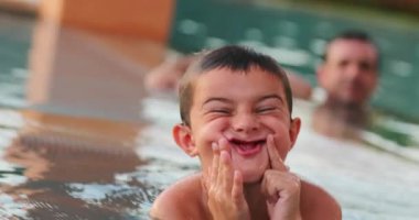 Küçük çocuk kameraya suratını buruşturarak komik yüzler yapıyor.