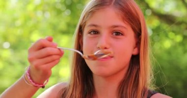 Küçük kız elinde kaşık tutuyordu.