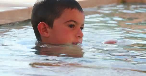 小男孩在游泳池里随意而坦率地喝水 — 图库视频影像