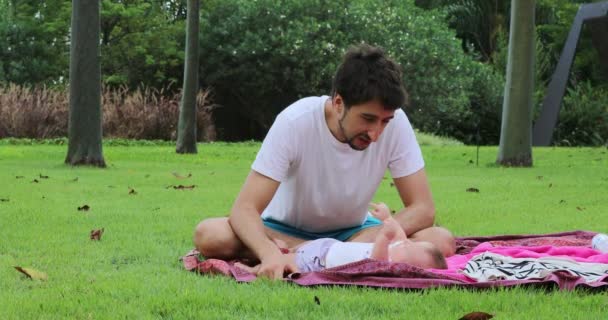 父亲在外面的大自然里和婴儿说话 坐在公园里 — 图库视频影像