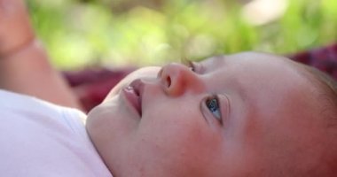 Happy cute newborn baby infant face closeup lying in grass outdoors
