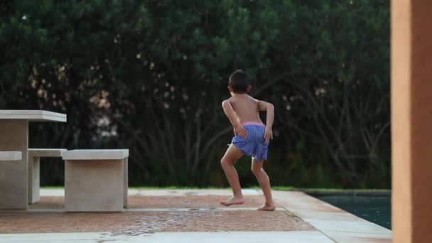 傻傻的小男孩在游泳池边跳舞 鬼鬼祟祟地笑着 摆出一副小丑的架势 — 图库视频影像