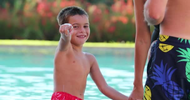 快乐的小男孩在外面的游泳池边手牵着妈妈的手 用手指对着相机 — 图库视频影像