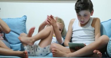 Children in front of screen devices tablets and smartphones at night wearing pajamas