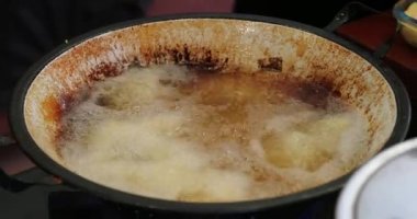 Frying food inside large boiling frying pan with oil