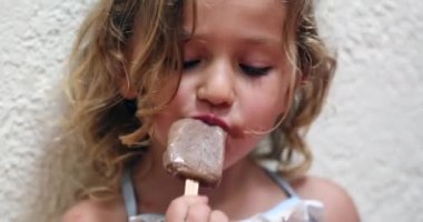 Candid small girl eating chocolate ice-cream