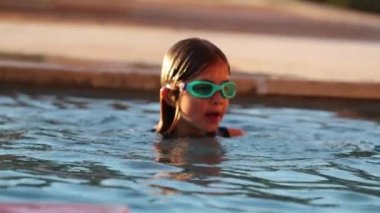 Yüzme havuzunda oynayan küçük kız yavaş çekimde suyun altına giriyor.