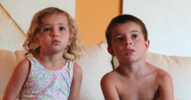 Çocuklar evlerinde televizyon seyrediyorlar. Kanepede çocuklar hipnotize oluyor.