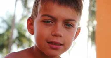 Portrait of of young boy child smiling to camera outside with lens-flare sunlight