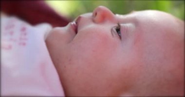 Mother kissing newborn baby infant outdoors