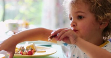 Little boy toddler wiping with napking in breakfast morning