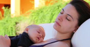 Mother and baby infant taking a nap together by the swimming pool outside