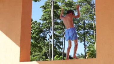 Çocuk platformun üstünde dans ediyor yaz tatillerinde havuzda neşe ve mutluluk hissediyor.