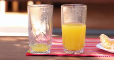 Empty and half full glass of orange juice