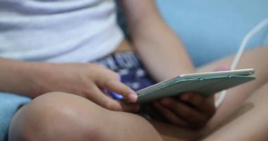 Child hands holding tablet touching screen