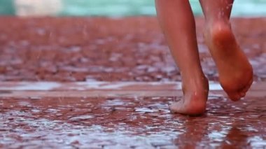 İki genç çocuk ağır çekimde yüzme havuzuna atlayıp koşuyor.