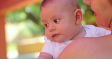 Mother holding newborn baby infant outdoors cute infant face