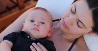 Mom and infant baby son together outside looking to camera