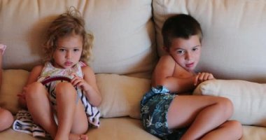 Çocuklar kanepede oturmuş film izliyorlar.