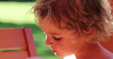 Portrait of cute little blonde boy eating melon fruit outdoors