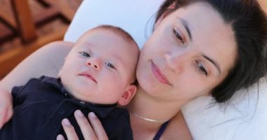 Portrait of mother and infant baby faces together laying down