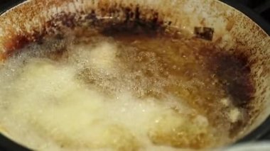 Frying food inside large boiling frying pan with oil in slow-motion