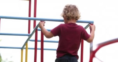Child boy holding on monkey bar outside