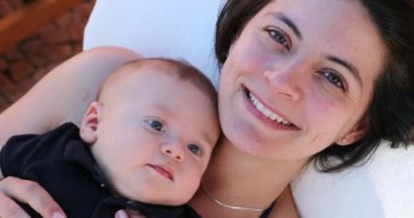 Mother holding baby infant layed down looking to camera