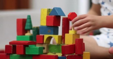 Kid hands stacking wooden toy building blocks
