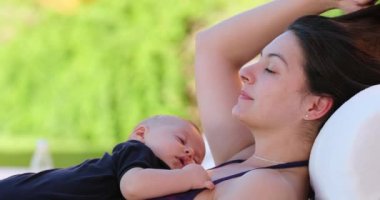 Young mother relaxing by the poolside drinking water