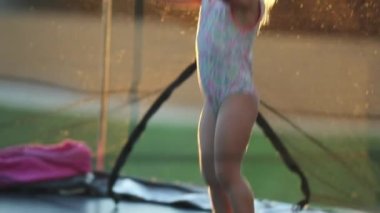 Mutlu küçük kız trambolinde hoplayıp zıplıyor