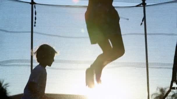 Kinderen Springen Buitenlucht Neer Trampoline Bij Zonsondergang — Stockvideo