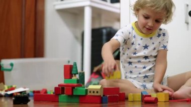 Candid child playing with building blocks in room