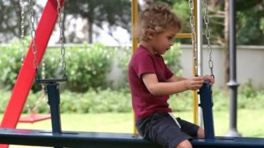 Cute baby toddler playing at playground swing