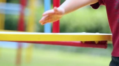 Closeup of child hand making carousel spin at playground outdoors